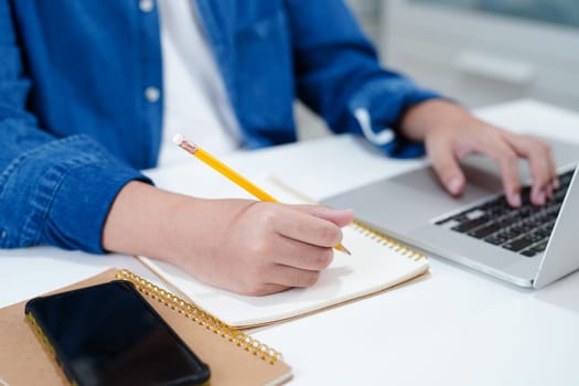 Asian teenage student write homework with laptop computer, learning university education concept.