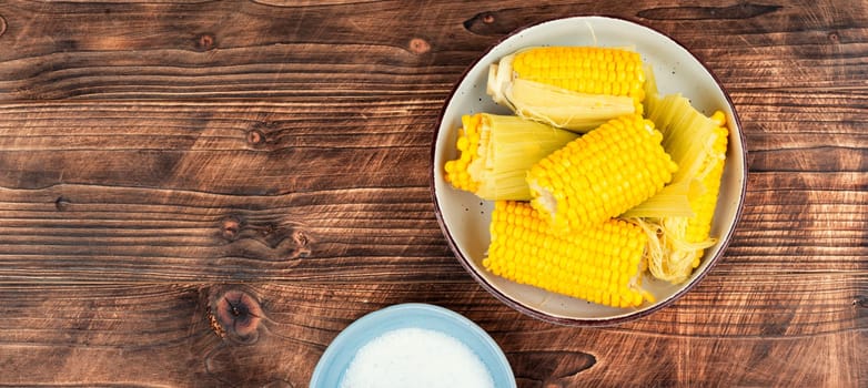 Sweet boiled corn on wooden background. Flavored boiled corn. Free space for your text.