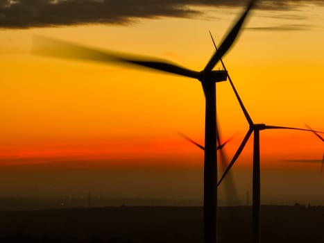 Wind farm field and sunset sky. Wind power. Sustainable, renewable energy. Wind turbines generate electricity. Sustainable development. Green technology for energy sustainability. Eco-friendly energy.