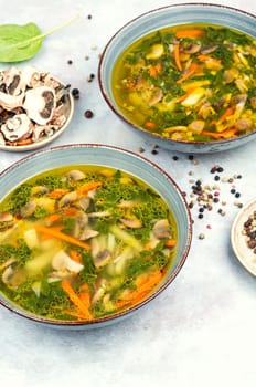 Homemade thick vegetarian mushroom soup with spinach and vegetables on rustic wooden table.