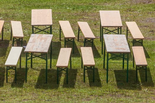 Wooden benches and folding tables standing on a meadow at an event, Germany