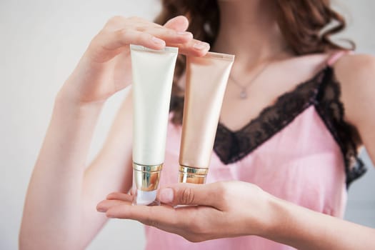 Skin care concept. Close up of female hands holding cosmetic cream tubes.