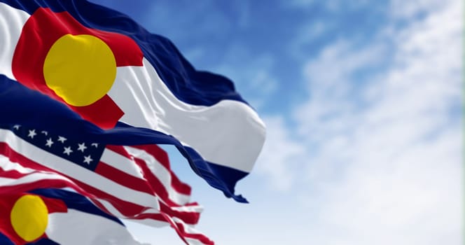 Colorado state flags waving with the national flags of the United States of America on a clear day. 3D illustration render. Rippled textile. Selective focus