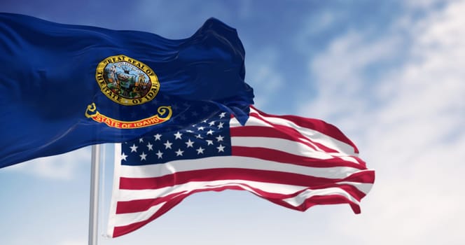 The Idaho state flag waving along with the national flag of the United States of America on a clear day. 3D illustration render. Rippled fabric. Selective focus