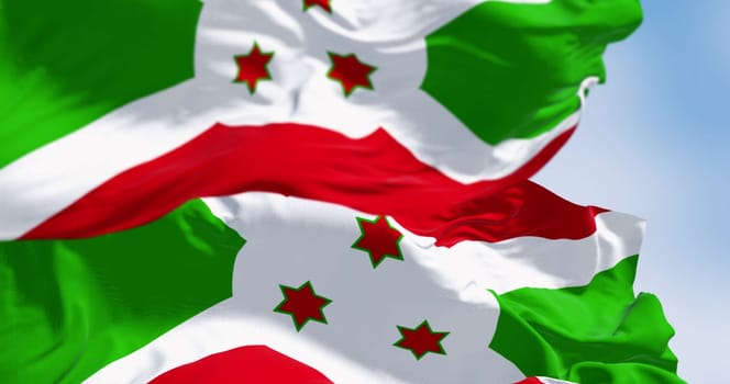 National flag of Burundi waving on a clear day. White diagonal cross dividing into red and green sections, three green stars in the center. 3d illustration render. Fluttering fabric. Selective focus