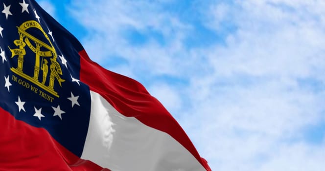Close-up of Georgia state flag waving in the wind on a clear day. Red, white, red stripes. Blue canton with 13 stars and coat of arms. 3d illustration render. Fluttering textile