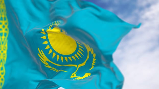 Close-up of Kazakhstan national flag waving on a clear day. Light blue field with a yellow sun and flying eagle in the center and a yellow ornamental band. 3d illustration render. Rippling fabric