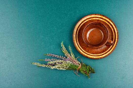 Fresh heather flowers with a cup of heather herbal tea on wooden table. Rustic style. Space for text.