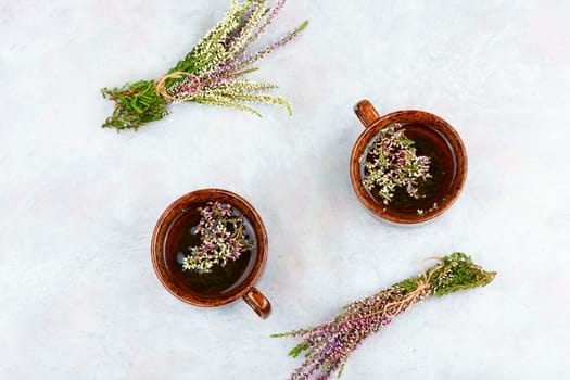 Fresh heather flowers with a cup of heather herbal tea on wooden table. Rustic style. Space for text.