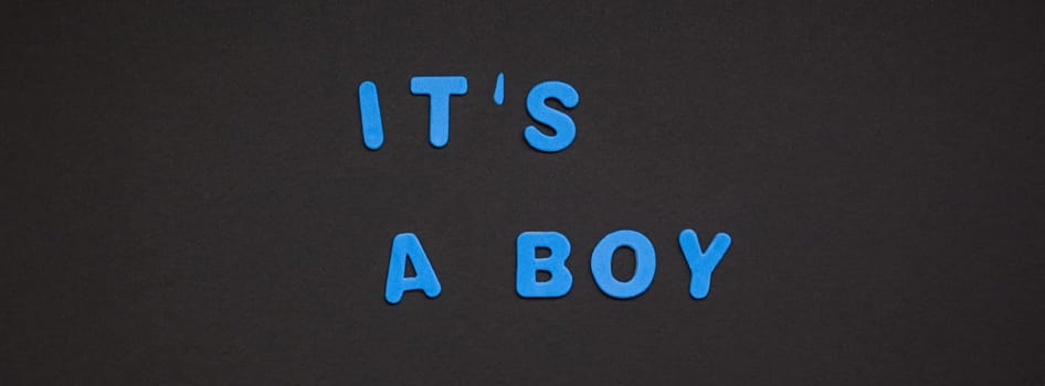 Creative blue text made from plastic letters It's a boy writing on black paper background with copy space. Baby shower concept, celebration card template