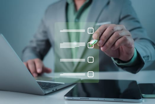 Businessman working on laptop and tablet productivity checklist and filling survey form online. Document management system DMS. Assessment form, questionnaire, Checklist and clipboard task management.