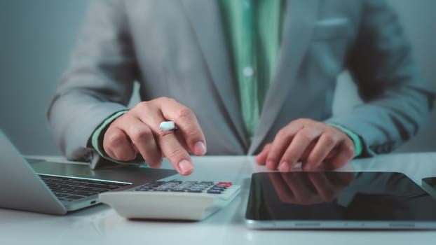 Accountant working with calculator and paperwork, Businessman calculating taxes and finances on laptop at corporate desk, Financial success, Economy concept, Man managing budget and market statistics.
