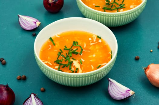 Fragrant onion soup in a ceramic bowl on a rustic wooden table.