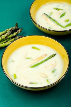 Cream soup with white and green asparagus in bowl. Flat lay.
