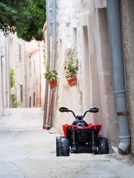 toy quad for kids parked in old narrow street of rab