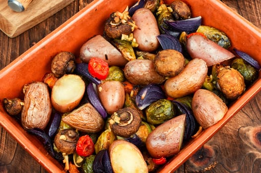 Roasted baked mushrooms, Brussels sprouts, and potatoes, garnished with onion in the oven dish. Free space for your text.