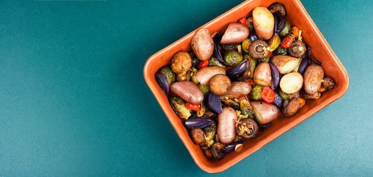 Roasted baked mushrooms, Brussels sprouts, and potatoes, garnished with onion in the oven dish. Free space for your text.