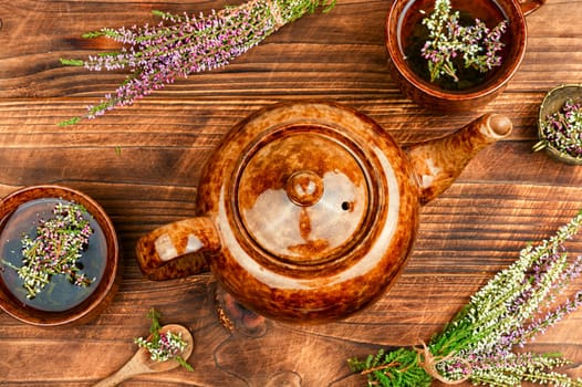 Glass tea cup with herbal heather tea on table. Herbal medicine, medicinal herbs. Top view.