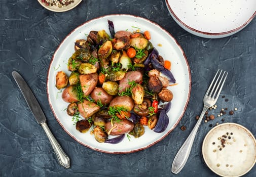 Roasted baked mushrooms, Brussels sprouts, and potatoes, garnished with onion in the oven dish. Free space for your text.