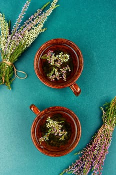 Glass tea cup with herbal heather tea on table. Herbal medicine, medicinal herbs. Top view.