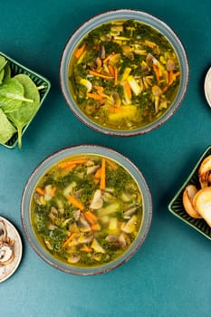 Fresh vegetarian soup filled with mushrooms, spinach with croutons on a table. Top view.