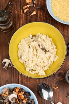 Millet porridge with mushrooms in a bowl on a rustic wooden background. Healthy food.