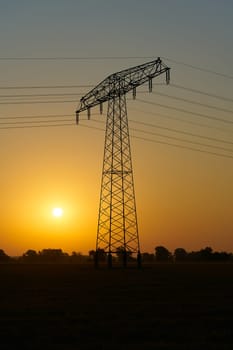 Atmospheric sunrise on a field with a power pole in the early morning in Germany