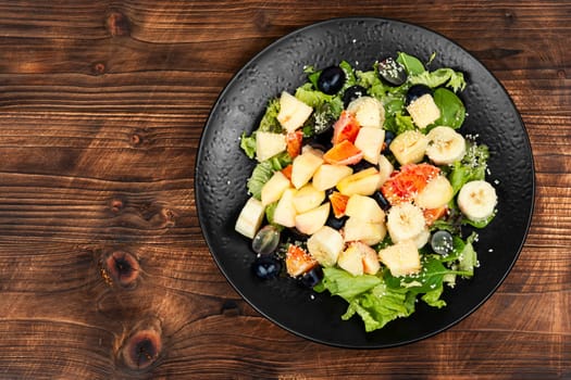 Fruit salad of red orange, apple, banana and lettuce. Healthy eating.
