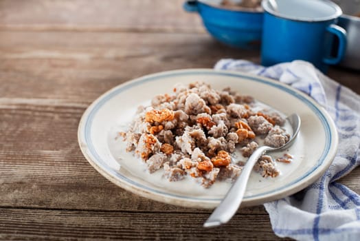 Slovenian traditional dish buckwheat mush served with pan-fried pork cracklings and lard, bowl warm milk close up shoot