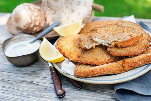 Macrolepiota procera parasol mushrooms breaded and crispy fried served on plate. Breaded in egg and breadcrumbs, then fried in oil