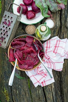 Bowl of Fresh Beetroot salad with oil and cumin seeds on wooden table in the garden