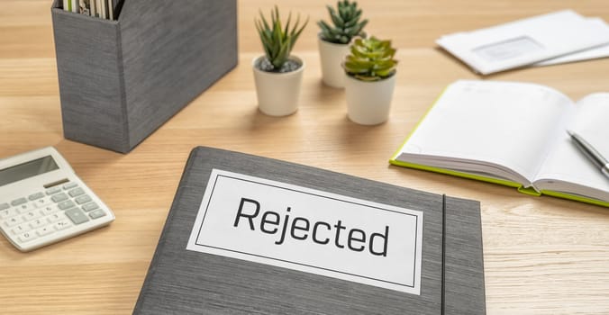 A folder on a desk with the label Rejected