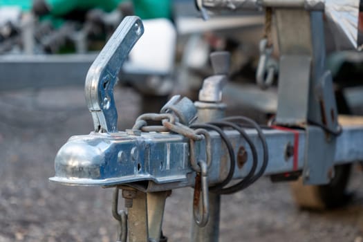 A rusty chain is attached to a trailer hitch. The chain is attached to a metal bar