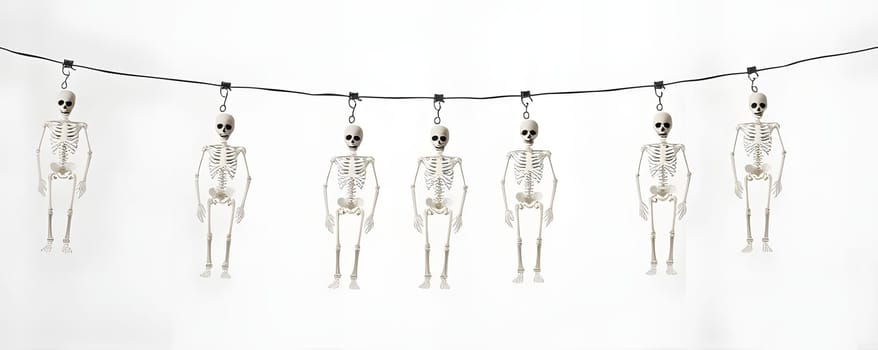 A string of small skeleton decorations hangs against a plain backdrop, adding a playful touch for Halloween festivities. These skeletons are evenly spaced, creating a spooky yet fun atmosphere.