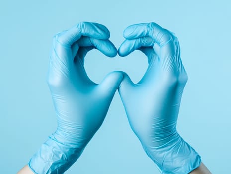 Blue-gloved hands forming a heart shape on a matching background, symbolizing care and compassion.