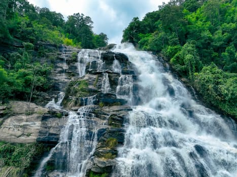 Aerial view of a waterfall in a lush tropical green forest in Doi Inthanon National Park, Chiang Mai, Thailand. This nature landscape showcases water sustainability and scenic travel destinations.