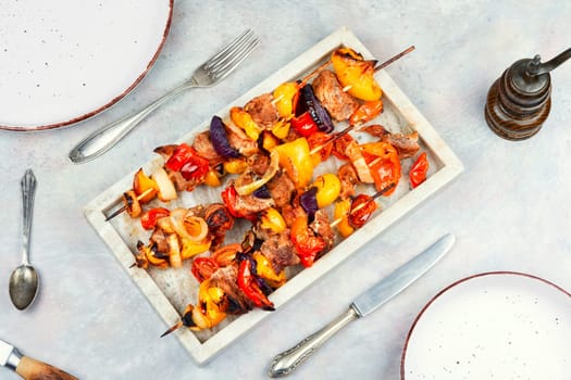 Meat kebabs with vegetables, shish kebab BBQ meat with onions. Top view with copy space.