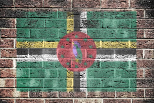 A Dominica flag painted on brick wall background green yellow black red sisserou parrot