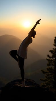 A person stands in a yoga pose atop a mountain, with arms stretched towards the sky. The vibrant sunset casts a warm glow over the landscape, creating a serene atmosphere.