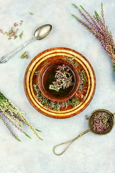 Fresh heather or Calluna vulgaris flowers with a cup of heather herbal tea. Herbal infusion.
