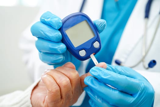 Asian doctor using digital glucose meter for check sample blood sugar level to treatment diabetes.