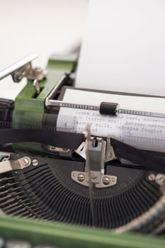 Vintage green typewriter machine with a sheet of paper and generic text typed, closeup photo