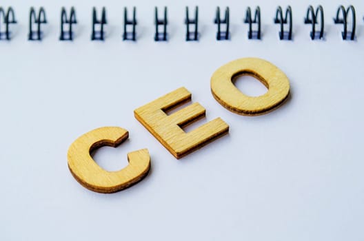 Top view of CEO wooden letters on white notepad. CEO representing Chief Executive Officer.