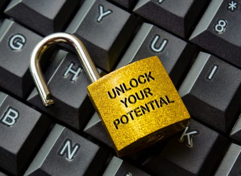 Unlock Your Potential text engraved on golden padlock with keyboard background. Motivational and Inspirational concept.