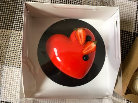 Red cake with strawberries in the shape of a heart top view. St. Valentine's Day sweets and gift.