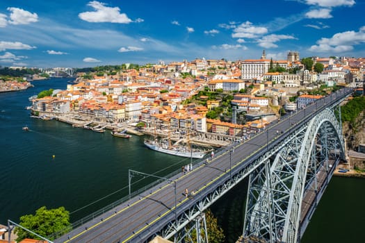 View of Porto city and Douro river with moored sailing ship and Dom Luis bridge I from famous tourist viewpoint Miradouro da Serra do Pilar on sunset. Porto, Vila Nova de Gaia, Portugal
