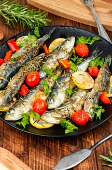 Oven baked italian fish sardoncini or sardines, with tomatoes, lemon and rosemary.