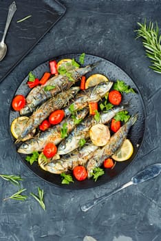 Oven baked italian fish sardoncini or sardines, with tomatoes, lemon and rosemary.