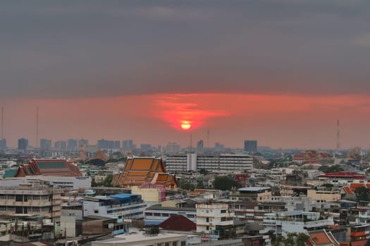 Colorful sunset over the skyline, cityscape of Bangkok, temples in the foreground and skyscrapers in the background, Thailand 2023