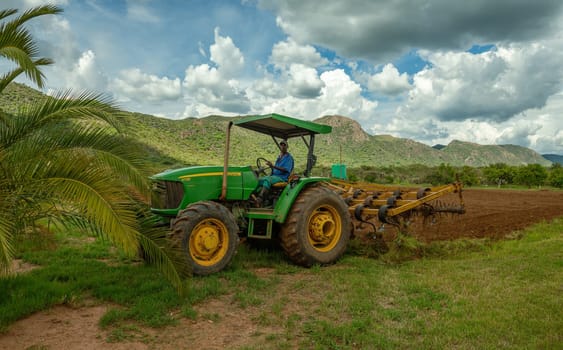 Farmer with green tractor prepares field for sowing, Otavi, Namibia